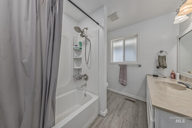 full bathroom with vanity, shower / bath combo, visible vents, and wood finished floors