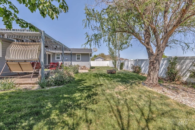 view of yard featuring an outdoor fire pit, a deck, and a fenced backyard