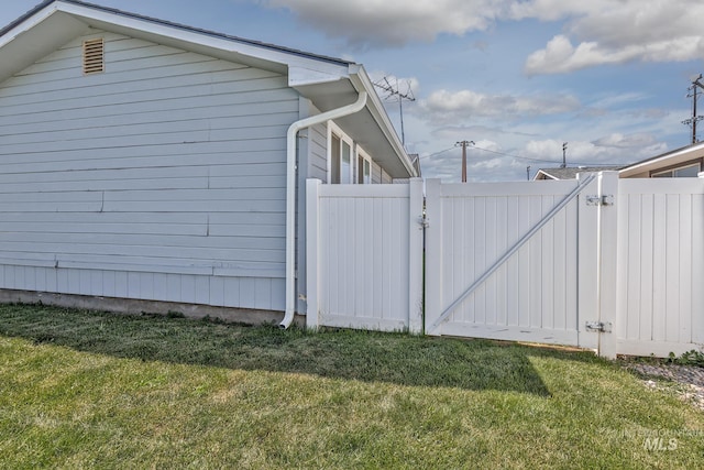 view of side of home featuring a lawn, fence, and a gate