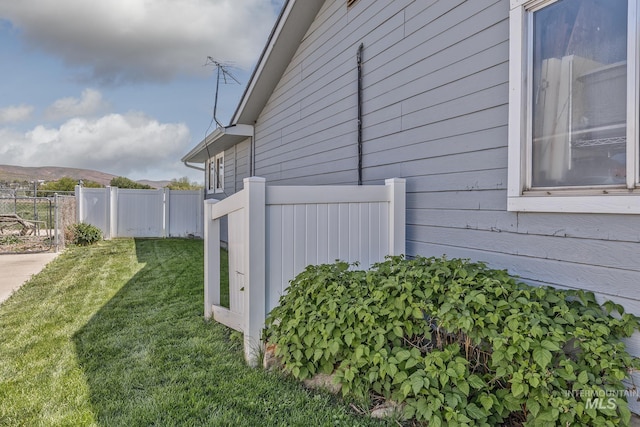 view of side of home with fence and a lawn