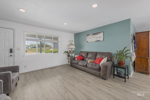 living room with light wood finished floors, baseboards, visible vents, and recessed lighting