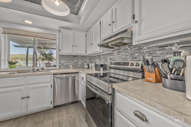kitchen featuring a sink, light wood-style floors, white cabinetry, under cabinet range hood, and appliances with stainless steel finishes