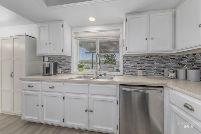 kitchen with a sink, tasteful backsplash, dishwasher, light countertops, and white cabinets