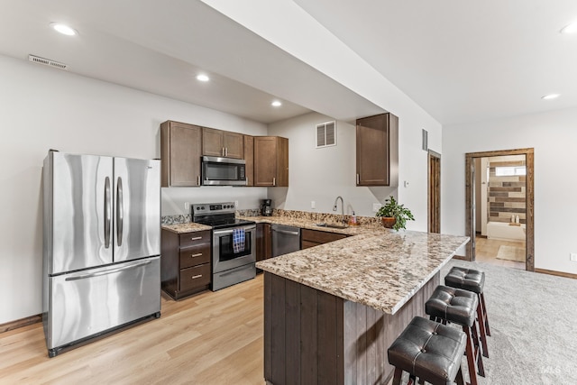 3383 Ridge Dr, Mccall, ID 83638 - kitchen with appliances with stainless steel finishes, a peninsula, light stone countertops, a kitchen breakfast bar, and light wood-style flooring