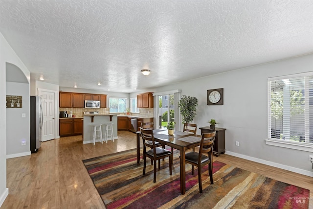 dining room with a textured ceiling, baseboards, and wood finished floors