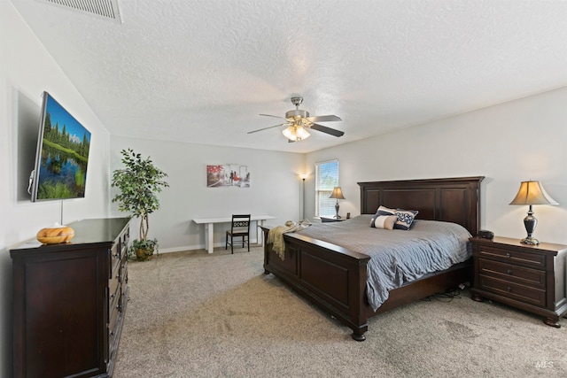 bedroom featuring baseboards, visible vents, ceiling fan, a textured ceiling, and light colored carpet