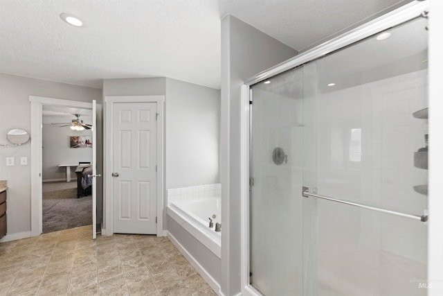 bathroom featuring vanity, a stall shower, ceiling fan, a textured ceiling, and a bath