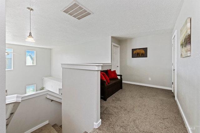 living area with visible vents, baseboards, carpet, an upstairs landing, and a textured ceiling