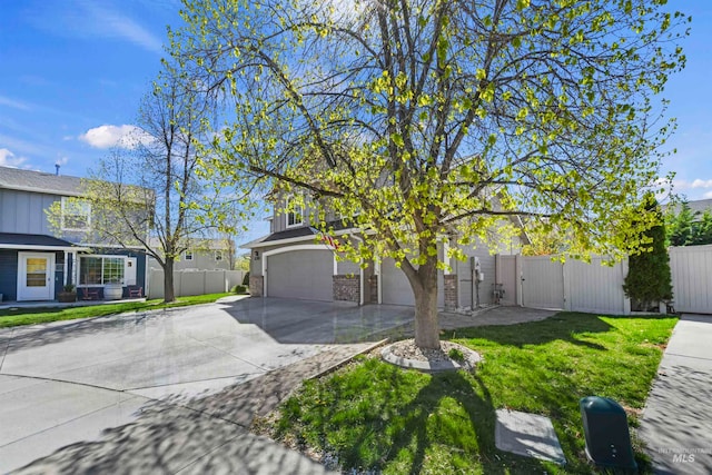 obstructed view of property with stone siding, concrete driveway, a front lawn, and fence