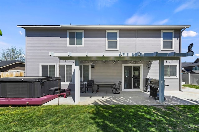 back of property with a patio area, a lawn, a hot tub, and fence