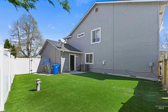 back of house with a fenced backyard, a yard, and a gate