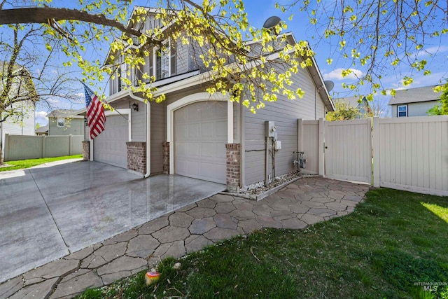 garage featuring a gate, fence, and driveway