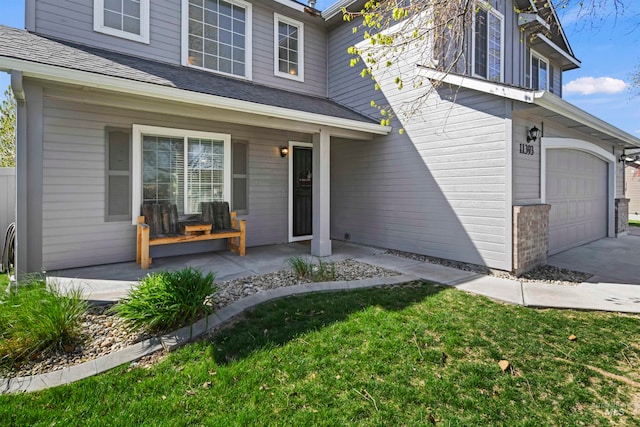 doorway to property featuring a porch, roof with shingles, a lawn, a garage, and driveway