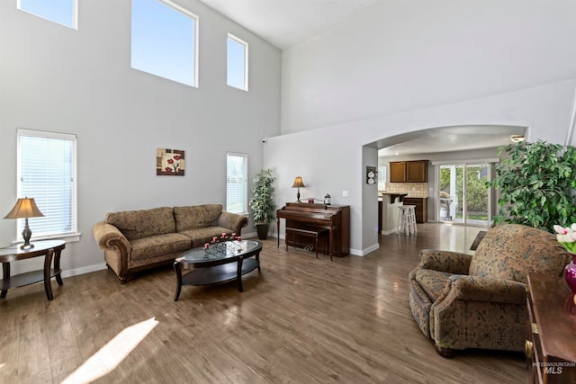 living area featuring wood finished floors, arched walkways, and baseboards