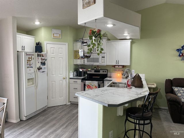 2329 S Garland St, Nampa, ID 83686 - kitchen with white appliances, a sink, a peninsula, white cabinets, and a breakfast bar