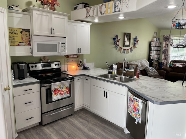2329 S Garland St, Nampa, ID 83686 - kitchen featuring stainless steel appliances, a peninsula, a sink, wood finished floors, and white cabinets