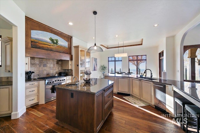 kitchen featuring dark hardwood / wood-style floors, cream cabinets, backsplash, and range with two ovens