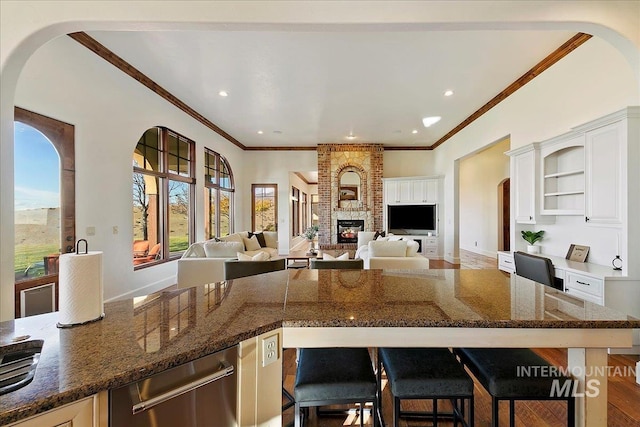 kitchen with hardwood / wood-style floors, a fireplace, white cabinetry, and brick wall