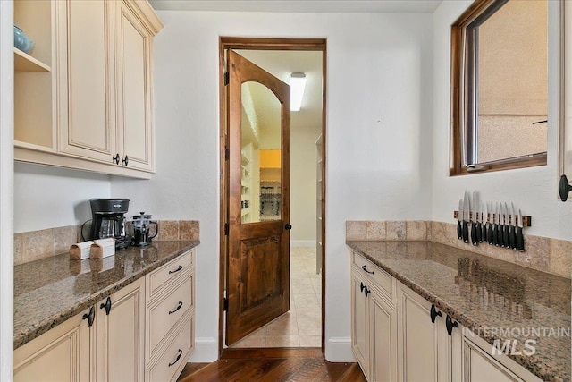 kitchen with tile flooring, dark stone countertops, and cream cabinetry