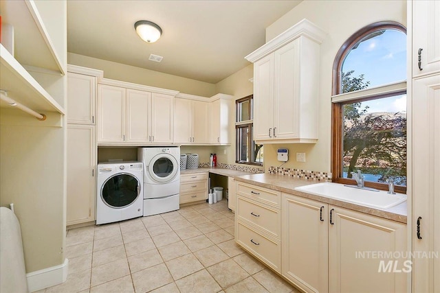 washroom featuring washer and dryer, sink, light tile floors, and cabinets