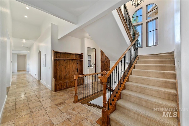 staircase with beamed ceiling, a high ceiling, and light tile floors