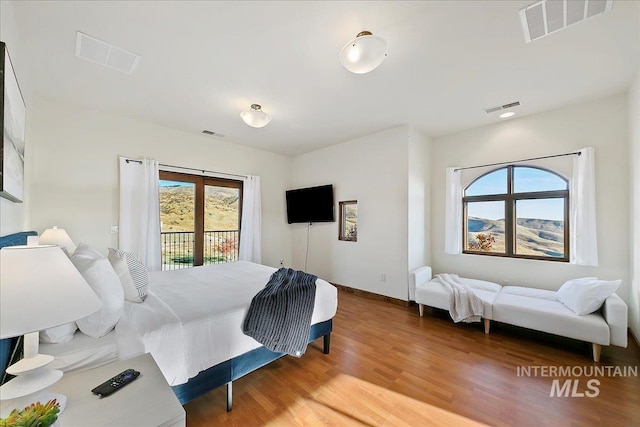 bedroom with access to outside and hardwood / wood-style floors