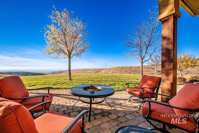 view of patio featuring an outdoor fire pit and a mountain view