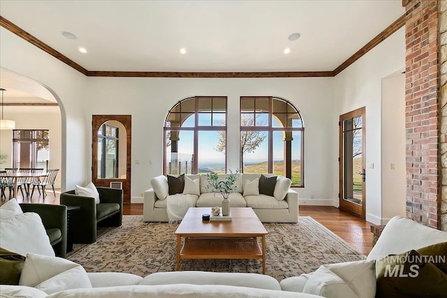 living room with ornamental molding, hardwood / wood-style flooring, and brick wall