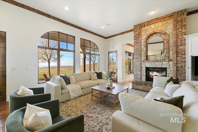 living room featuring ornamental molding, a fireplace, wood-type flooring, and brick wall