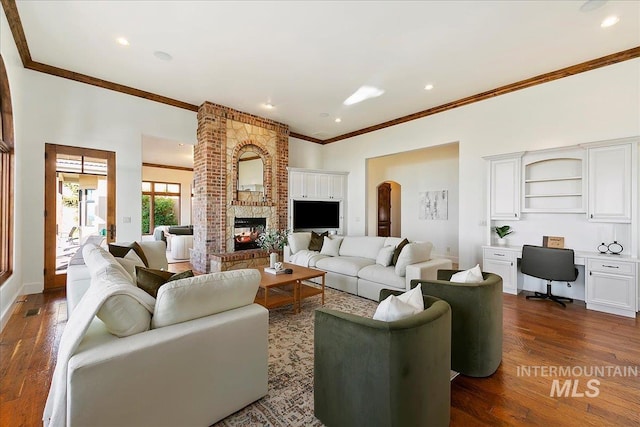 living room with brick wall, a brick fireplace, dark hardwood / wood-style floors, and crown molding