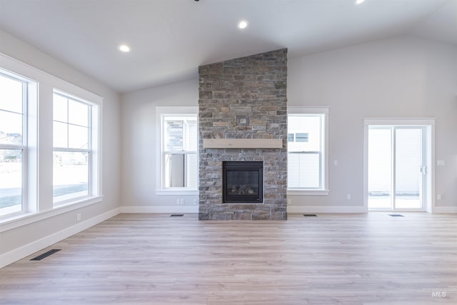 unfurnished living room featuring a stone fireplace, vaulted ceiling, and light hardwood / wood-style floors