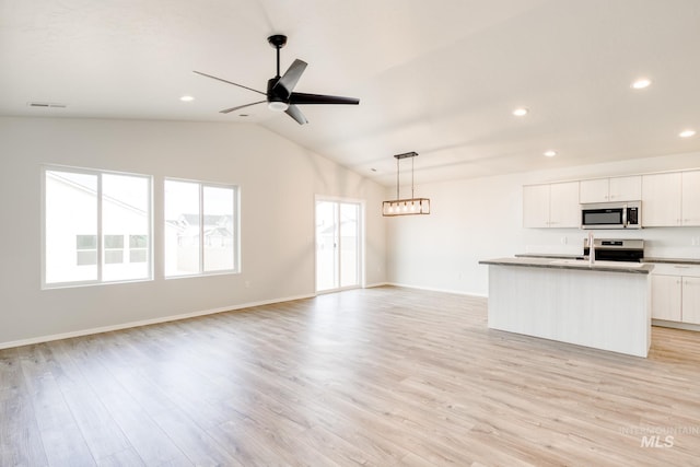 kitchen with lofted ceiling, stainless steel appliances, visible vents, and open floor plan