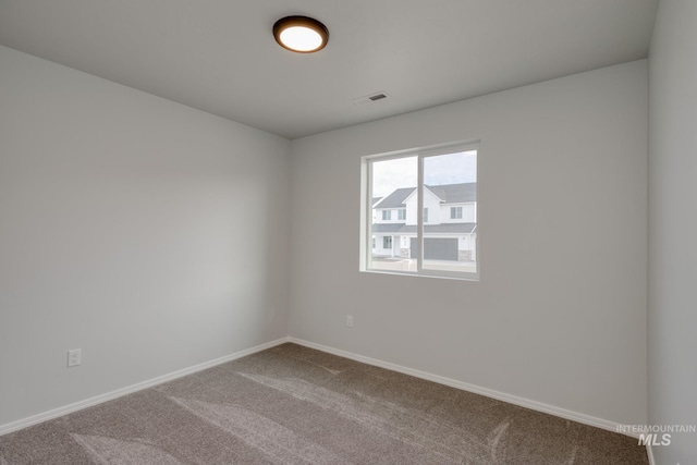 carpeted spare room featuring visible vents and baseboards