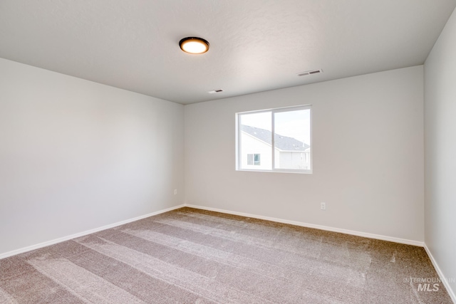 carpeted spare room with baseboards and visible vents