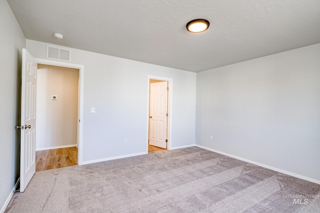 carpeted spare room with visible vents and baseboards
