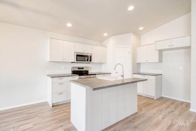 kitchen featuring light wood finished floors, a sink, baseboards, a center island with sink, and appliances with stainless steel finishes