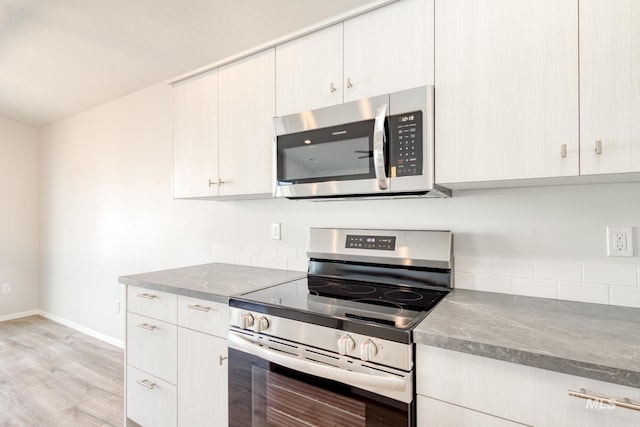 kitchen featuring tasteful backsplash, light wood-type flooring, appliances with stainless steel finishes, and baseboards