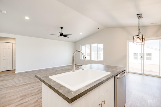 kitchen with stainless steel dishwasher, a sink, light wood-style floors, decorative light fixtures, and an island with sink