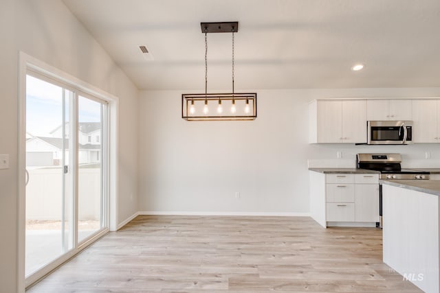 kitchen with white cabinets, baseboards, light wood-style floors, and appliances with stainless steel finishes