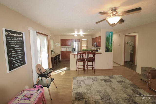 275 E Aruba, Meridian, ID 83642 - kitchen featuring stainless steel appliances, a peninsula, a breakfast bar area, a ceiling fan, and light wood-style flooring