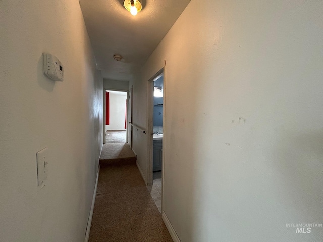 hall featuring baseboards and light colored carpet