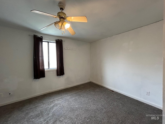 spare room featuring visible vents, dark carpet, baseboards, and ceiling fan