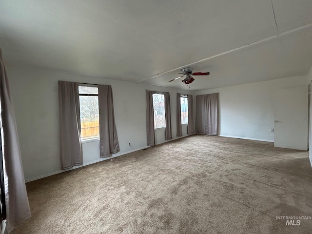 empty room with carpet flooring, ceiling fan, and baseboards