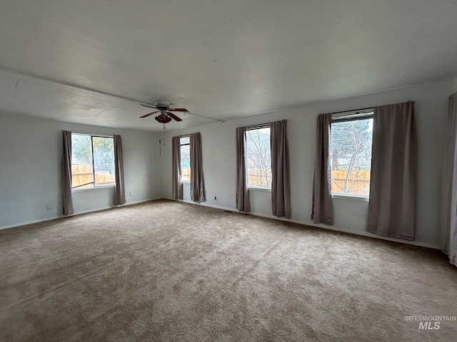 carpeted spare room with baseboards and a ceiling fan