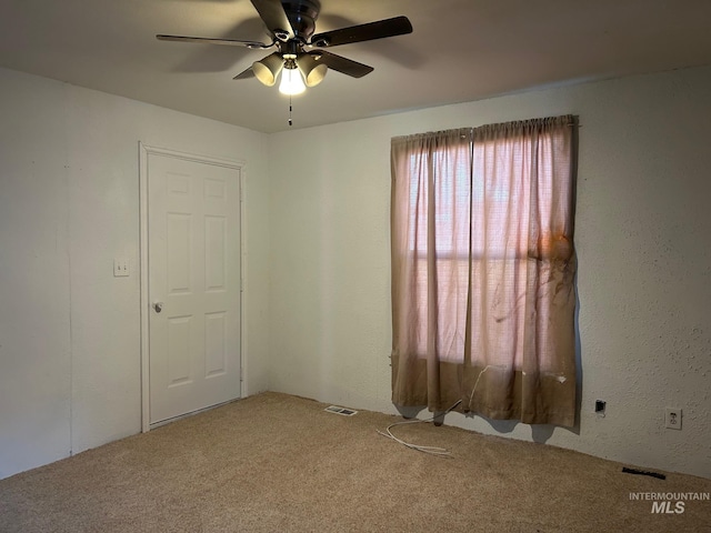 spare room with ceiling fan, carpet floors, and visible vents