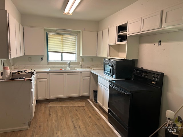 kitchen featuring white cabinets, light countertops, light wood-type flooring, black appliances, and a sink