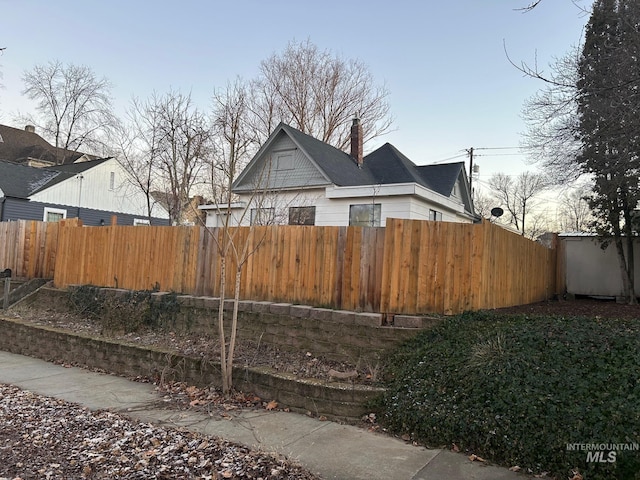 view of property exterior featuring a chimney and fence