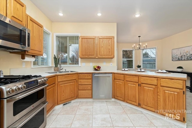 kitchen with visible vents, a peninsula, a sink, light countertops, and appliances with stainless steel finishes