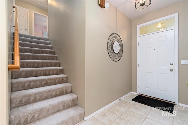 entrance foyer featuring stairway, light tile patterned flooring, and baseboards