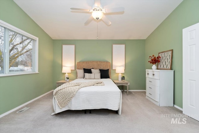 bedroom with a ceiling fan, visible vents, baseboards, lofted ceiling, and light colored carpet